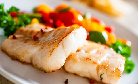 Baked Fish with tomatoes, peppers, and onions on a plate