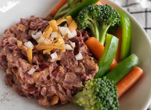 Bean dip on a plate with broccoli and carrots on the side