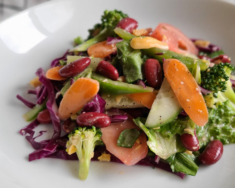 salad with beans, carrots, lettuce, cucumbers, and broccoli on a plate